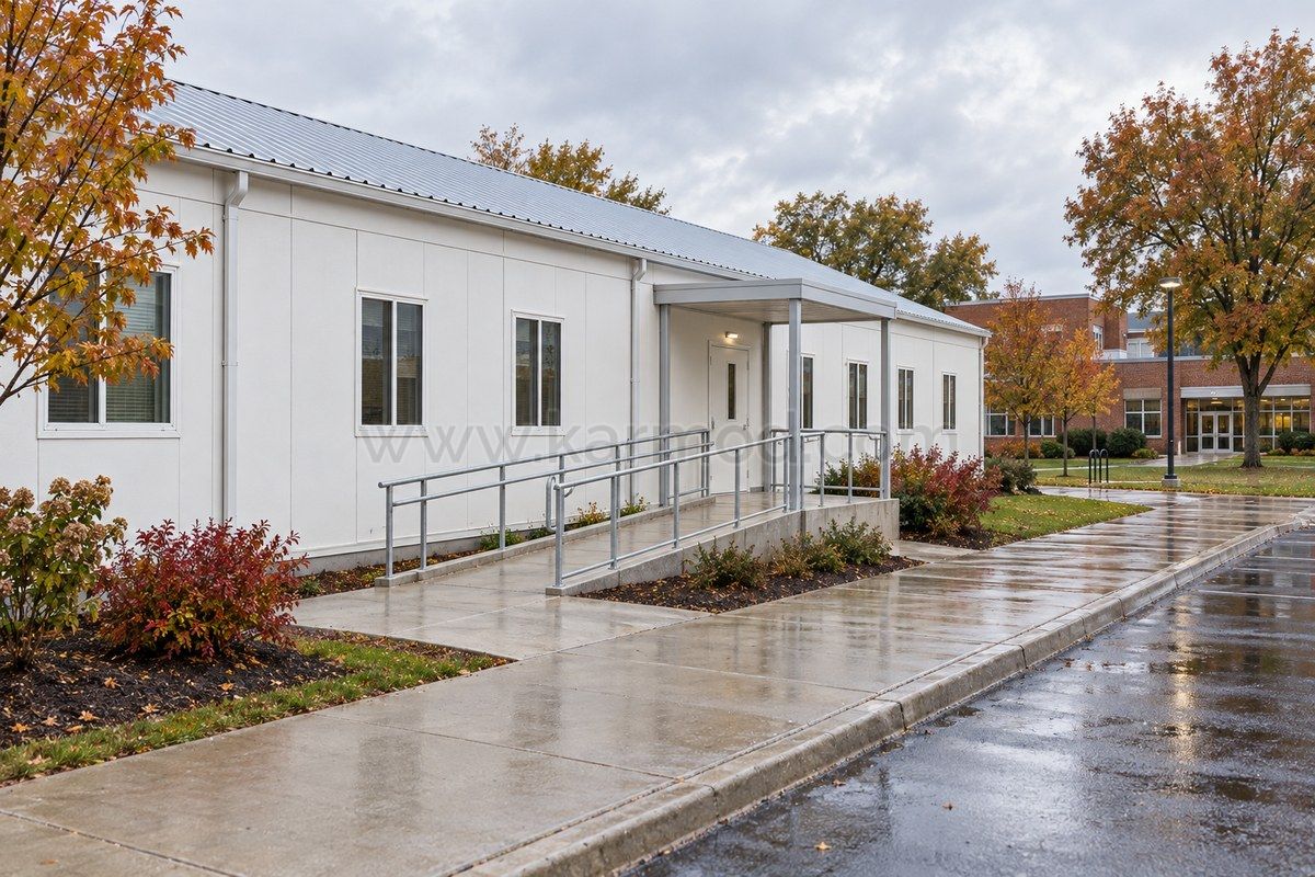 Entrée d’une salle de classe modulaire avec rampe, palier et auvent reliant le bâtiment aux cheminements du campus