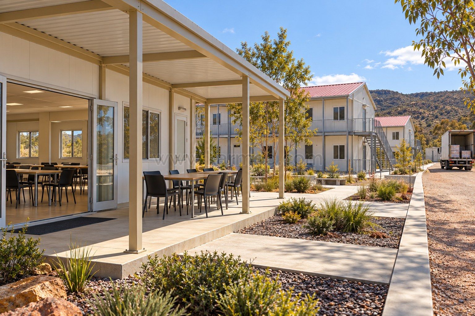 Sala común modular abierta a una terraza sombreada con mesas y circulación exterior.