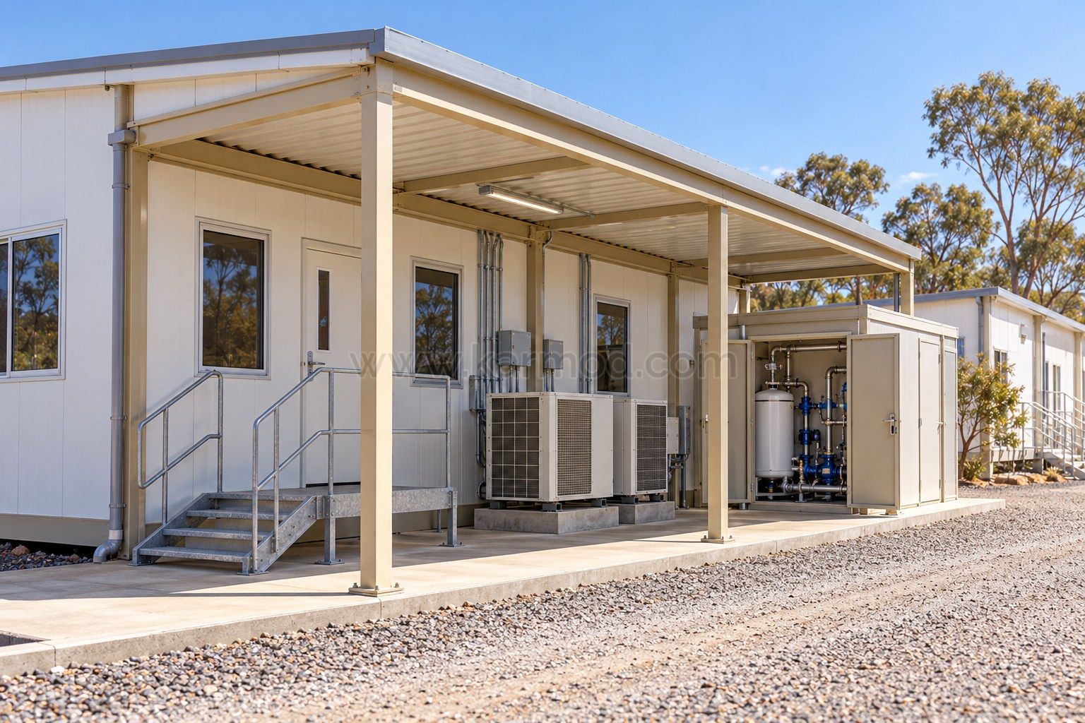 Acceso técnico modular con equipos de climatización y armario de agua junto a una vía de mantenimiento.