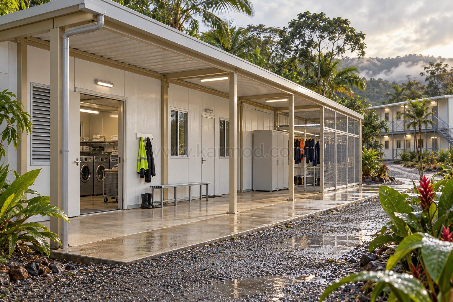 Visualización de una lavandería modular con alero amplio, acceso de servicio cubierto y zona ventilada junto a vegetación tropical.