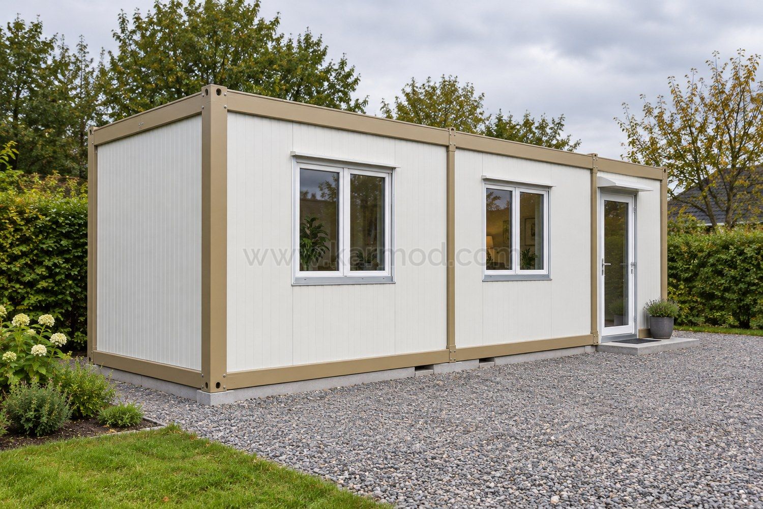 Module à toit plat, panneaux blancs et ossature beige, avec une allée de gravier devant la façade