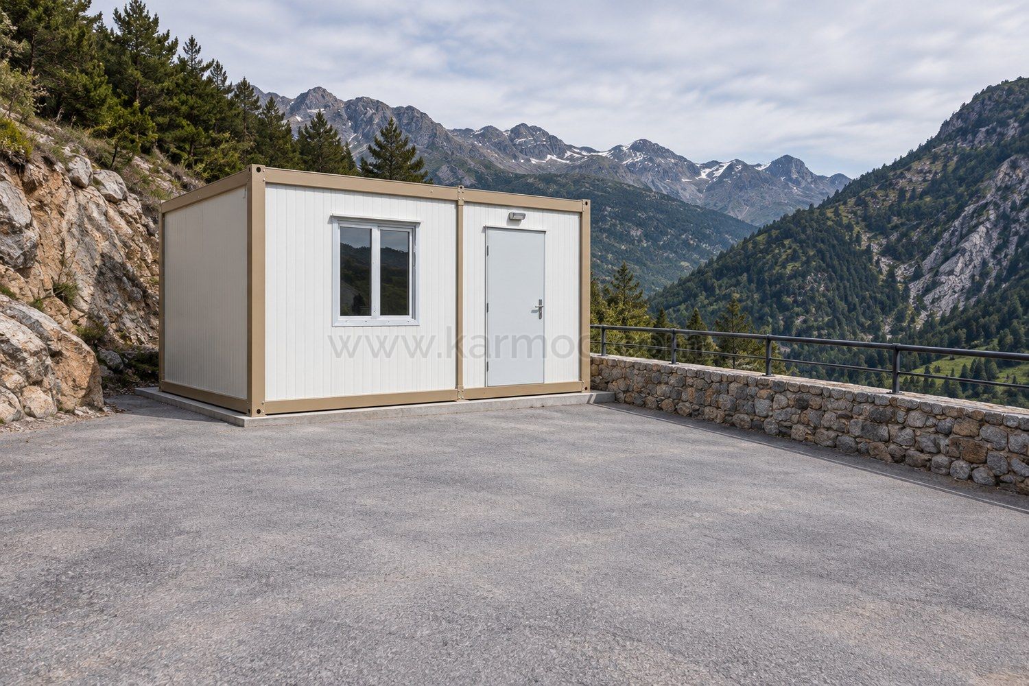 Petit module à panneaux blancs sur une plateforme plane bordée d’un muret, devant un paysage montagneux