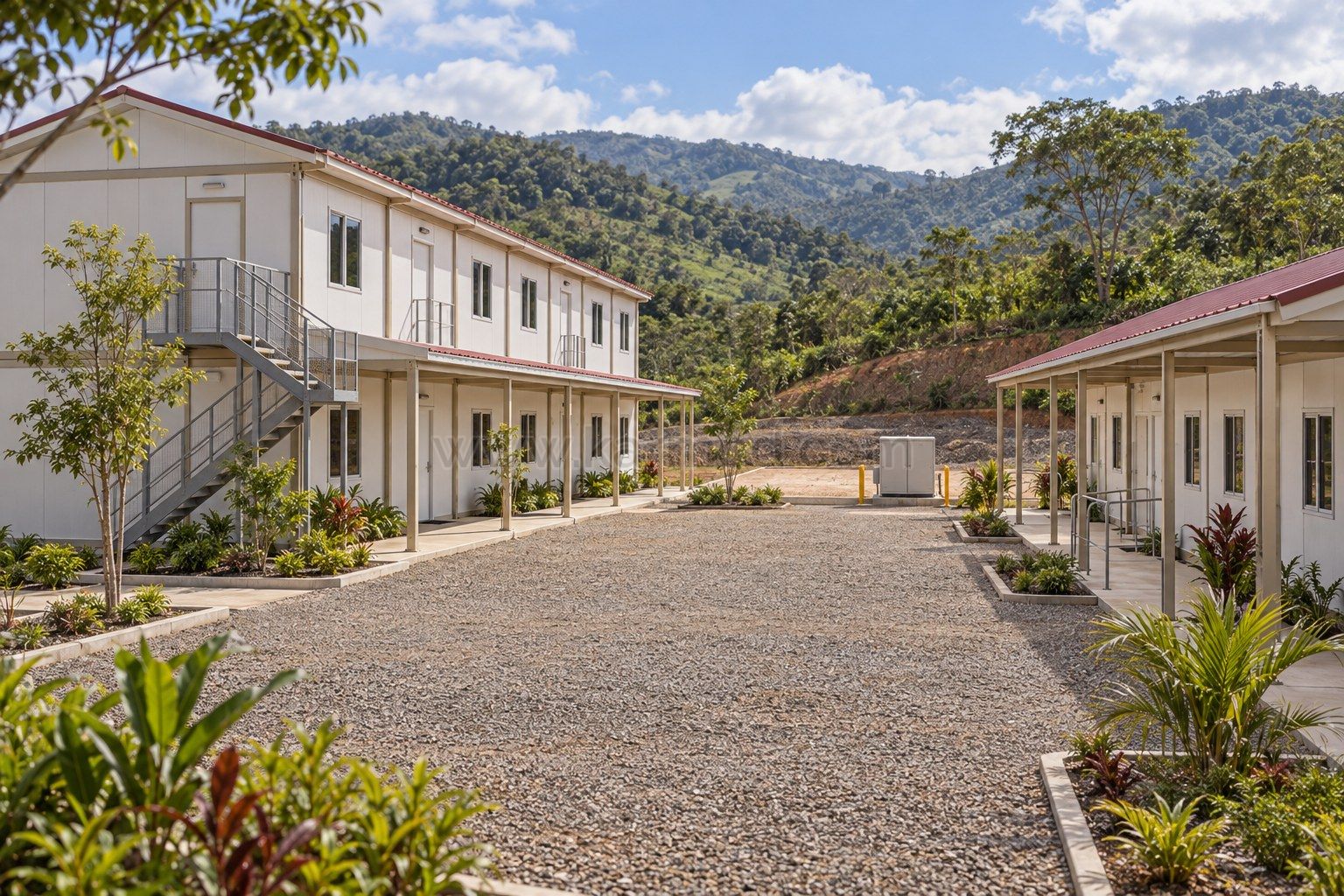 Visualización de edificios modulares con cubiertas rojizas, pasos cubiertos y una plataforma libre para ampliación en un paisaje de laderas verdes.